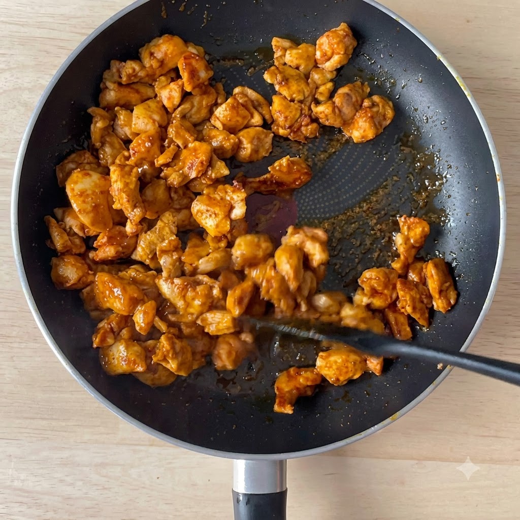Salsa de soja vertiéndose en una sartén con trozos de pollo dorados.