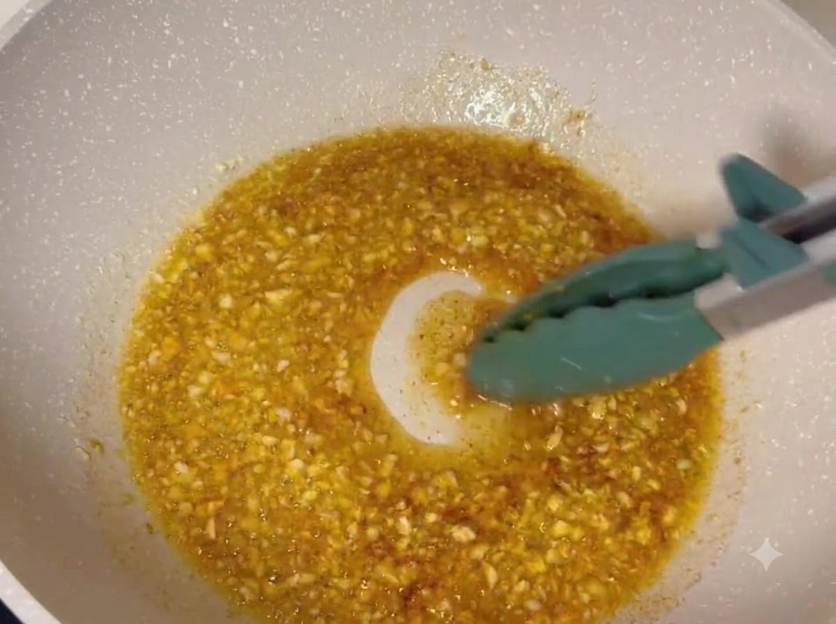 Muslos de pollo frito siendo bañados en un glaseado de mantequilla y ajo burbujeante dentro de una sartén.