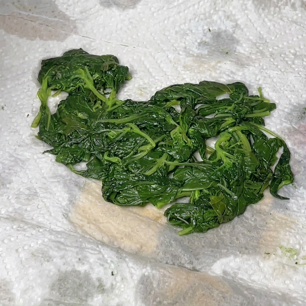 Albahaca, parmesano, piñones y aceite de oliva combinados dentro de un procesador de alimentos.