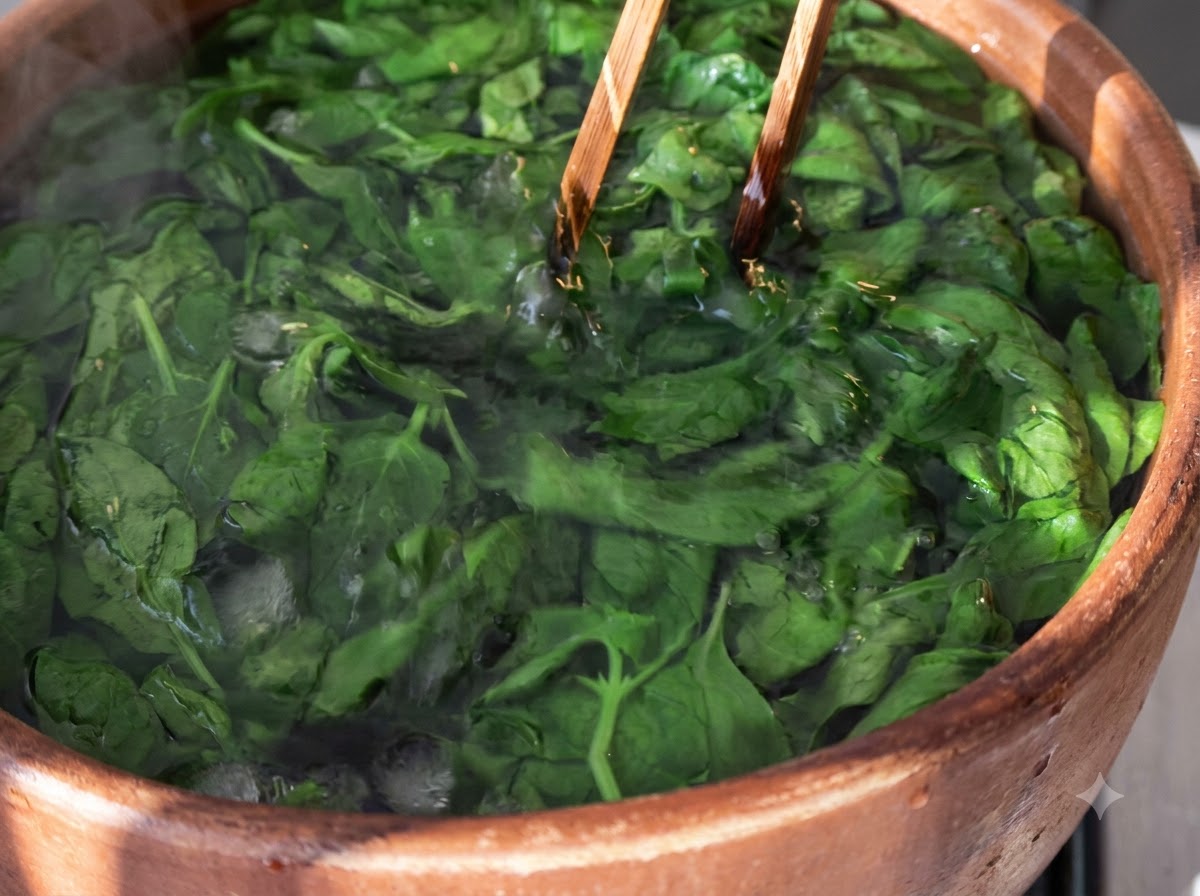 Hojas de albahaca escaldadas sumergidas en agua con hielo dentro de un bol de madera con palillos de madera.